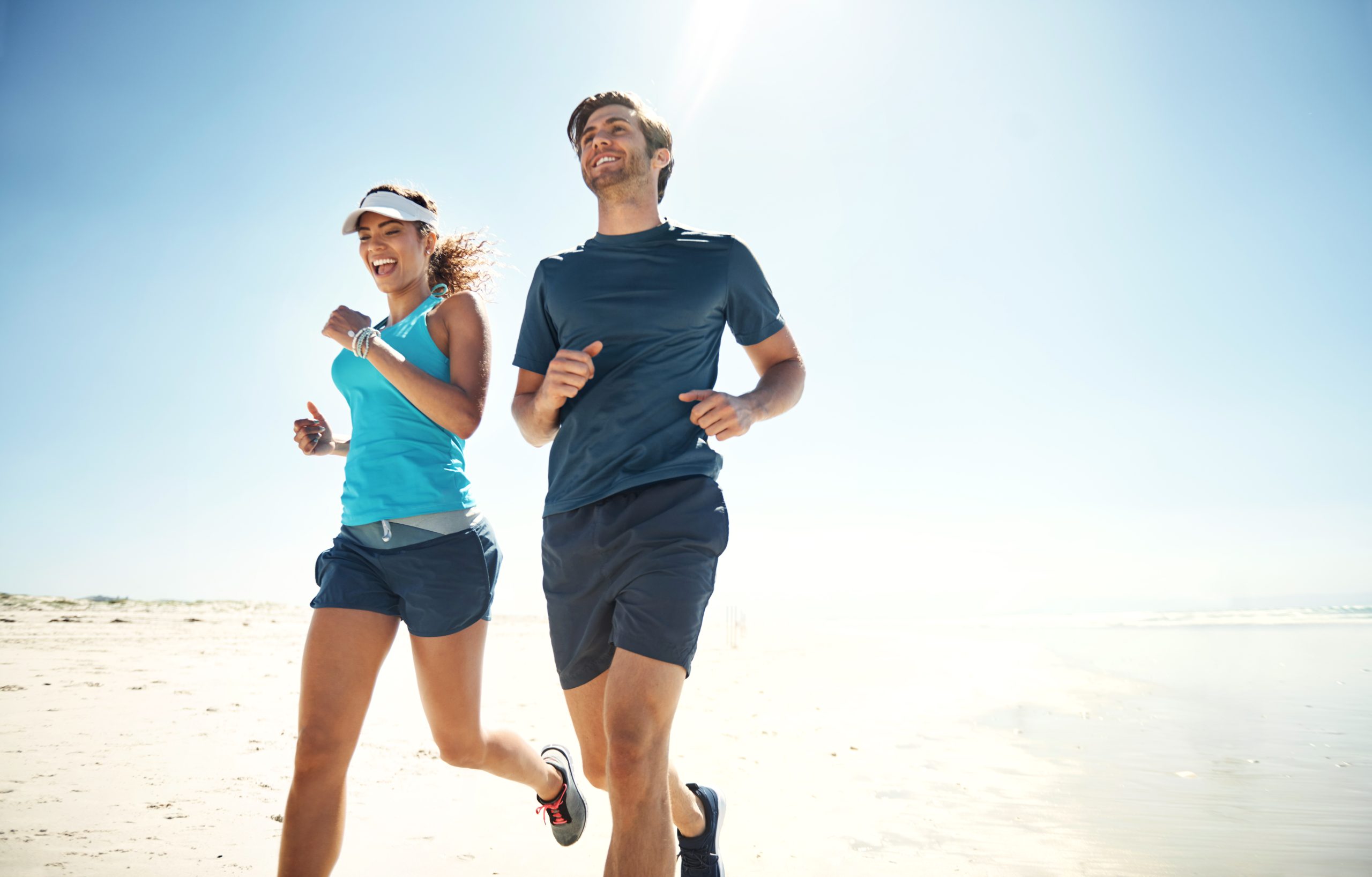 Shot of a young couple running along the beach together